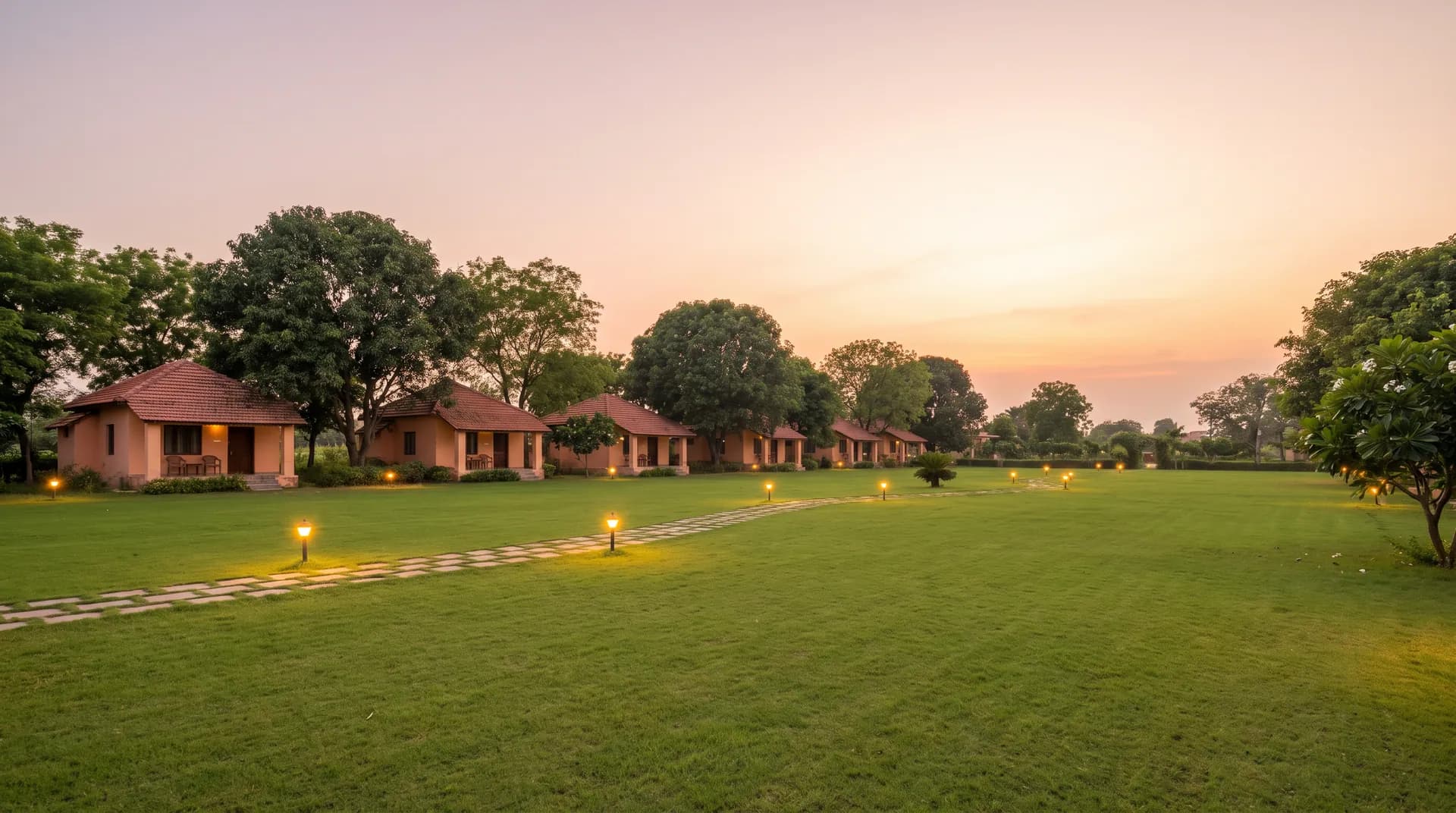 Lawn at dusk with a row of cottages and garden lamps along the path